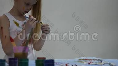 可爱的小女孩画家在桌子上<strong>画画</strong>，在她的衣服上<strong>画画</strong>。 慢动作